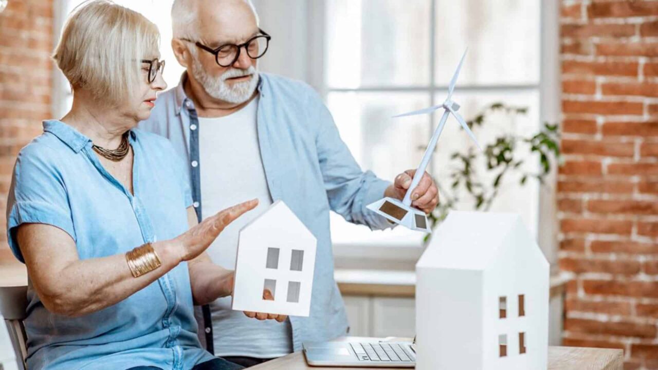 Senior Couple Holding a house and wind turbine model.